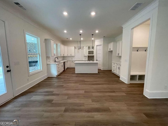 kitchen with white cabinetry, dark hardwood / wood-style flooring, a kitchen island, and crown molding