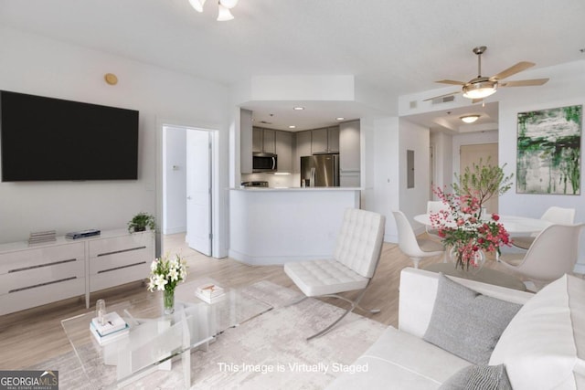 living room with ceiling fan, light hardwood / wood-style floors, and electric panel