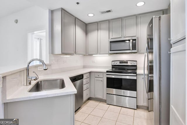 kitchen with gray cabinets, sink, light tile patterned floors, and appliances with stainless steel finishes