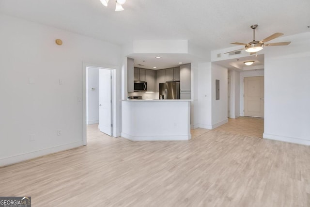 unfurnished living room with electric panel, light hardwood / wood-style floors, and ceiling fan