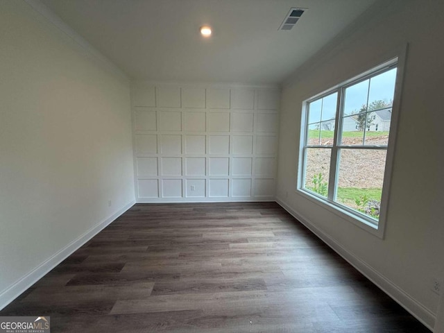 empty room featuring ornamental molding and dark wood-type flooring