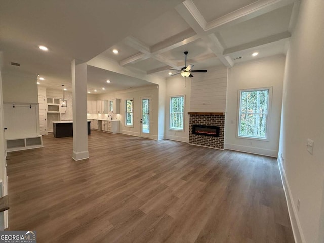 unfurnished living room with ceiling fan, dark wood-type flooring, beamed ceiling, and a healthy amount of sunlight