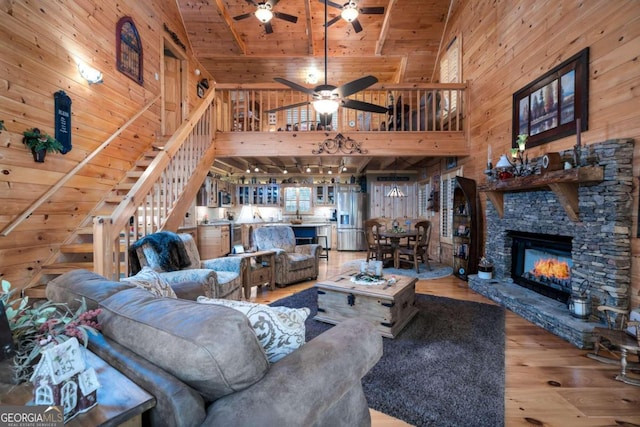 living room with a stone fireplace, high vaulted ceiling, wood walls, wood ceiling, and hardwood / wood-style flooring