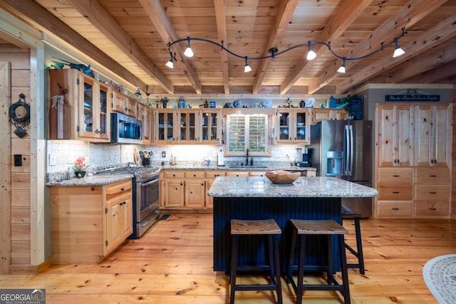 kitchen featuring beamed ceiling, light hardwood / wood-style floors, light stone counters, and stainless steel appliances