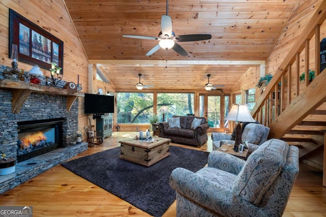 living room featuring light hardwood / wood-style floors, wood walls, wood ceiling, and a fireplace