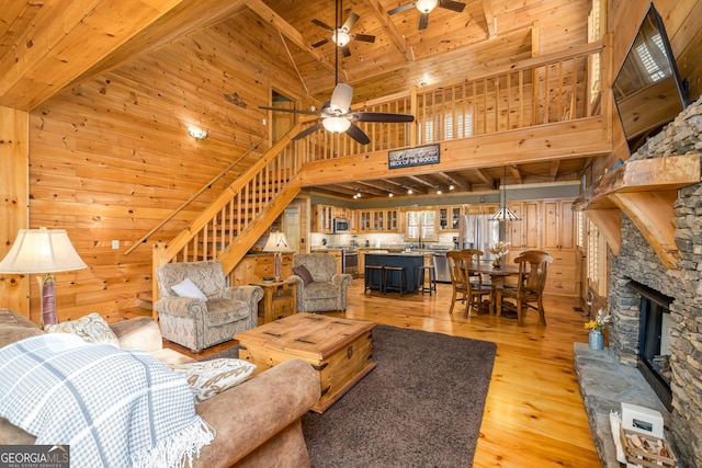 living room with light wood-type flooring, wooden ceiling, high vaulted ceiling, and wooden walls