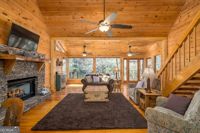 living room featuring lofted ceiling, a stone fireplace, wooden walls, light wood-type flooring, and wood ceiling