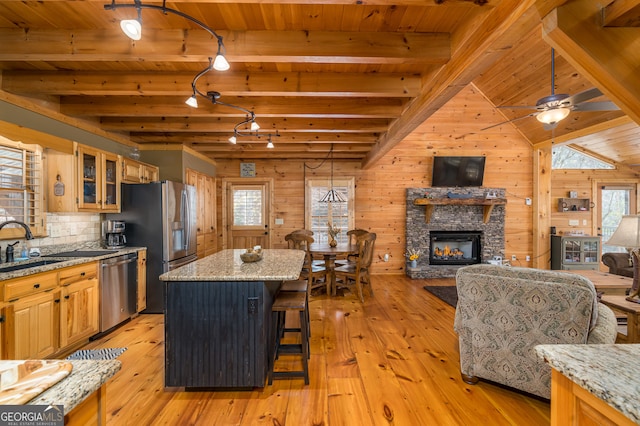 kitchen with light stone countertops, wood walls, a center island, and stainless steel appliances