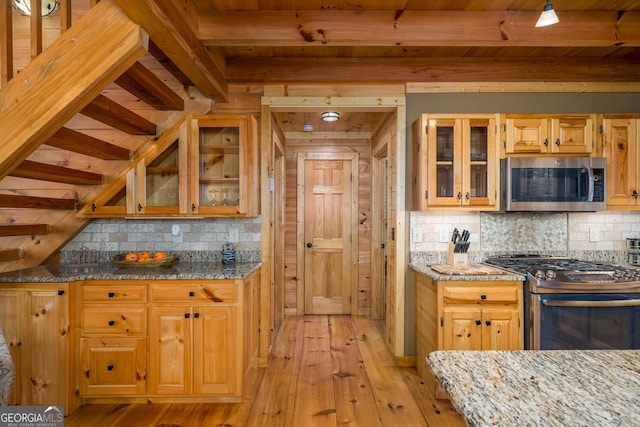 kitchen featuring decorative backsplash, light stone countertops, stainless steel appliances, and light hardwood / wood-style flooring