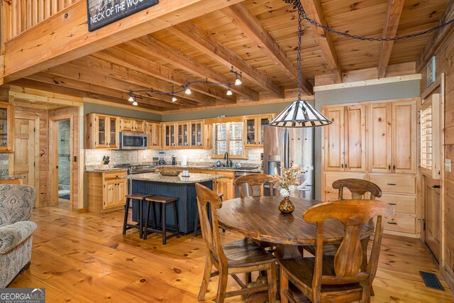 dining area with wooden walls, beamed ceiling, wooden ceiling, and light wood-type flooring