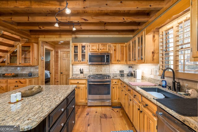 kitchen with beamed ceiling, light stone countertops, and appliances with stainless steel finishes