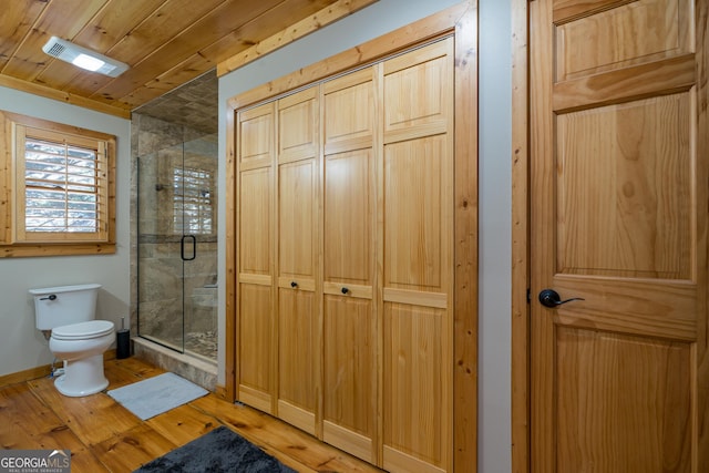 bathroom featuring hardwood / wood-style floors, toilet, a shower with shower door, and wooden ceiling