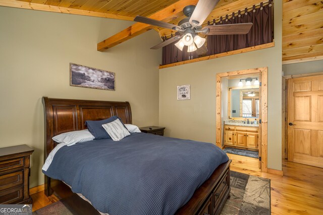 bedroom with ensuite bath, ceiling fan, lofted ceiling with beams, wood ceiling, and light wood-type flooring