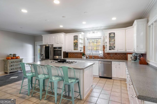 kitchen featuring a breakfast bar, stainless steel appliances, a center island, white cabinetry, and light tile patterned flooring