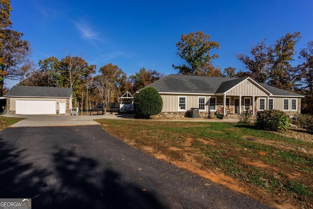 single story home with a porch, a garage, an outdoor structure, and a front lawn