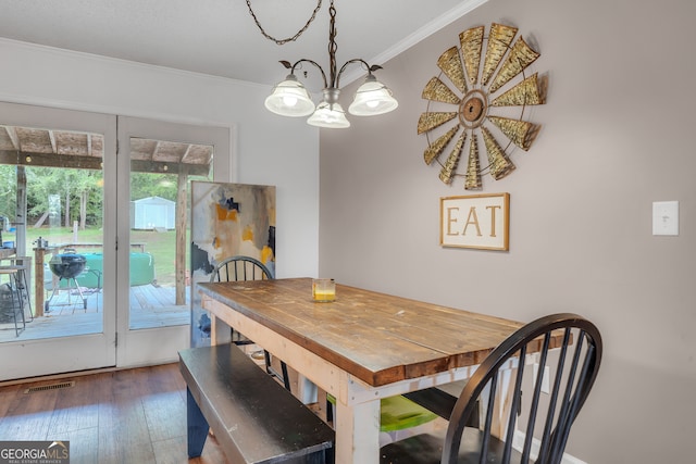 dining area featuring crown molding, dark wood-type flooring, and a notable chandelier