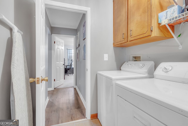 laundry room featuring cabinets, separate washer and dryer, and light hardwood / wood-style flooring