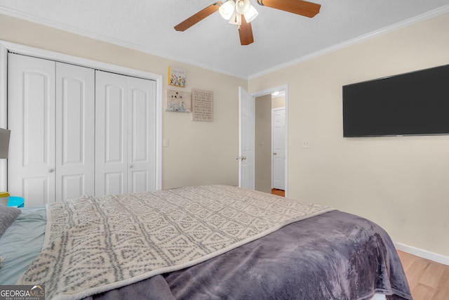 bedroom with ceiling fan, wood-type flooring, ornamental molding, and a closet