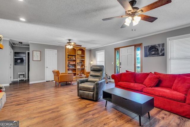 living room featuring ceiling fan, wood-type flooring, a textured ceiling, and ornamental molding