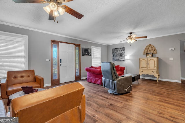 living room featuring hardwood / wood-style floors, a textured ceiling, ceiling fan, and ornamental molding