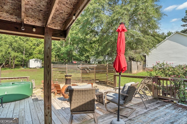 wooden deck with a storage shed and a lawn