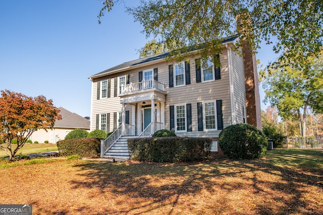 colonial-style house with a balcony and a front lawn