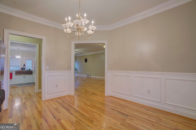 unfurnished dining area with crown molding, a chandelier, and light wood-type flooring