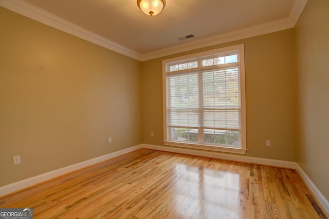 spare room featuring crown molding, plenty of natural light, and light wood-type flooring