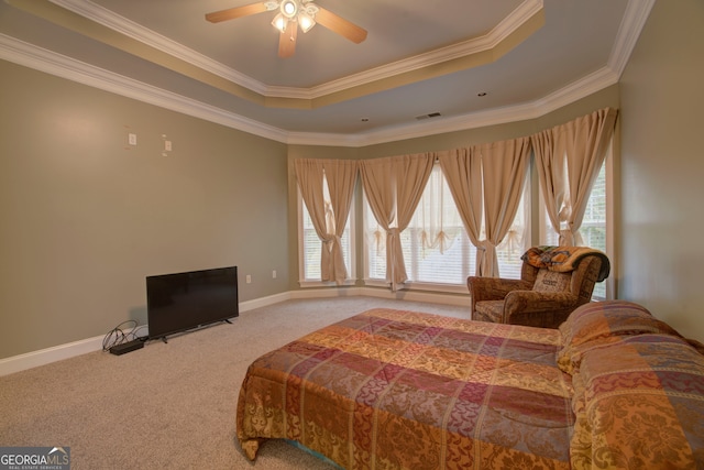 carpeted bedroom with a tray ceiling, multiple windows, crown molding, and ceiling fan