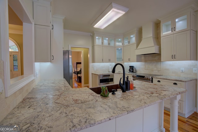 kitchen featuring appliances with stainless steel finishes, white cabinets, and custom exhaust hood