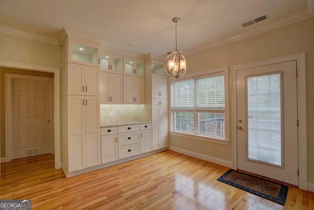 kitchen with pendant lighting, light hardwood / wood-style floors, ornamental molding, and tasteful backsplash