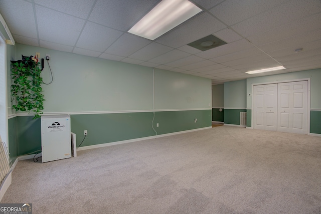 carpeted spare room with a drop ceiling