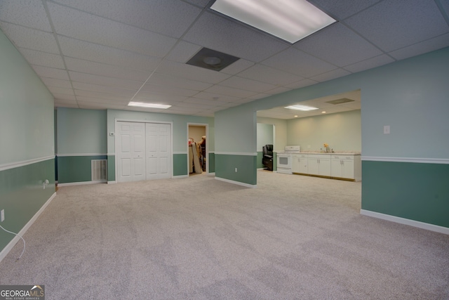 basement with a drop ceiling, carpet floors, and sink