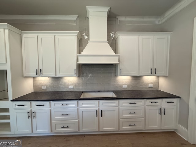 kitchen featuring white cabinets, custom range hood, and black electric stovetop