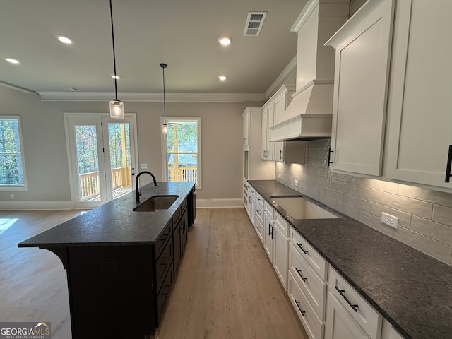 kitchen with a kitchen island with sink, sink, stainless steel cooktop, and a healthy amount of sunlight