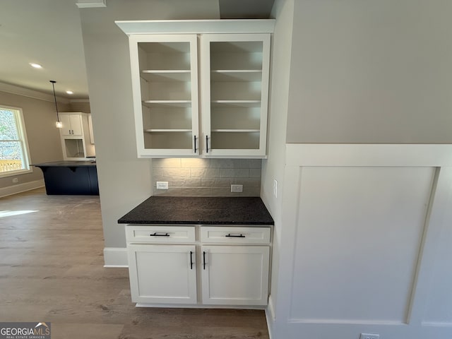 bar with decorative backsplash, crown molding, white cabinets, and light hardwood / wood-style floors