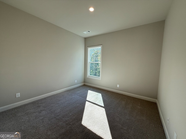 spare room with dark carpet