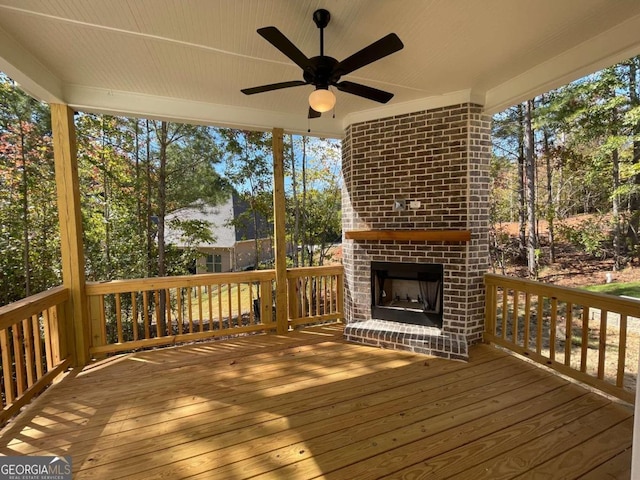 deck with ceiling fan and an outdoor brick fireplace