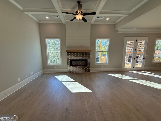 unfurnished living room with ceiling fan, a fireplace, a healthy amount of sunlight, and wood-type flooring