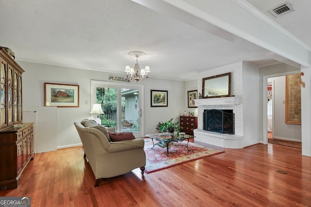 living room featuring a fireplace, a textured ceiling, hardwood / wood-style flooring, and ornamental molding