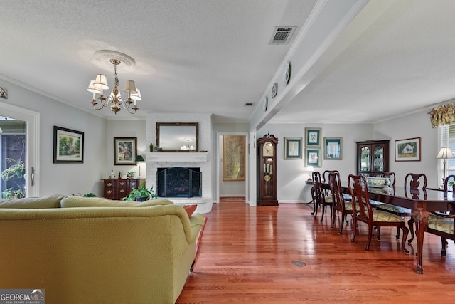 living room with hardwood / wood-style floors, a textured ceiling, a fireplace, and a chandelier