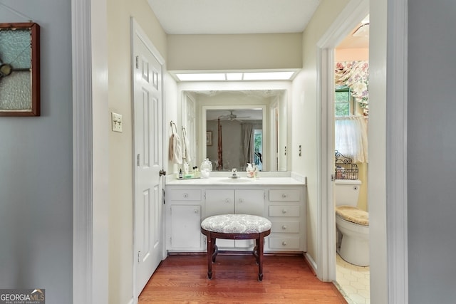 bathroom with vanity, hardwood / wood-style flooring, toilet, and ceiling fan