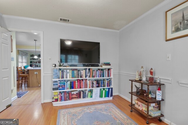 sitting room featuring ornamental molding and hardwood / wood-style flooring