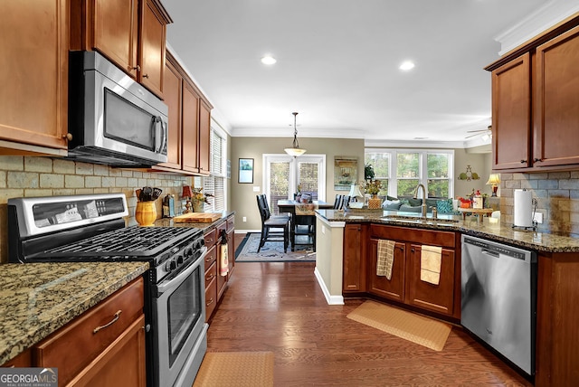 kitchen featuring stainless steel appliances, hanging light fixtures, dark wood-type flooring, and dark stone countertops