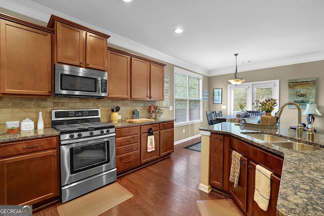 kitchen with pendant lighting, dark wood-type flooring, sink, ornamental molding, and appliances with stainless steel finishes