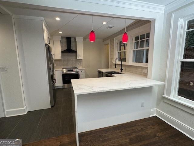 kitchen with white cabinetry, wall chimney range hood, kitchen peninsula, and appliances with stainless steel finishes