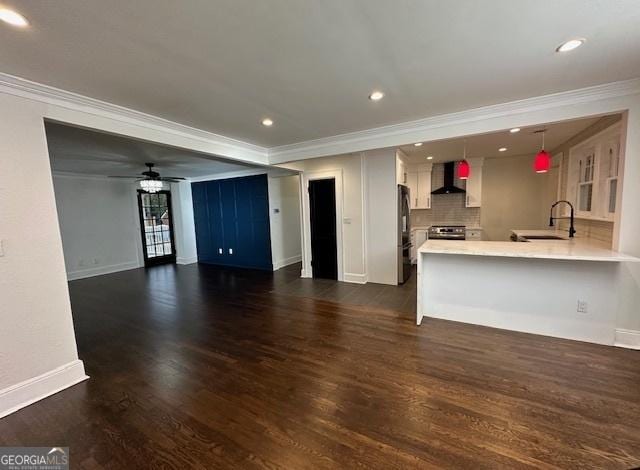 unfurnished living room featuring crown molding, ceiling fan, dark hardwood / wood-style flooring, and sink