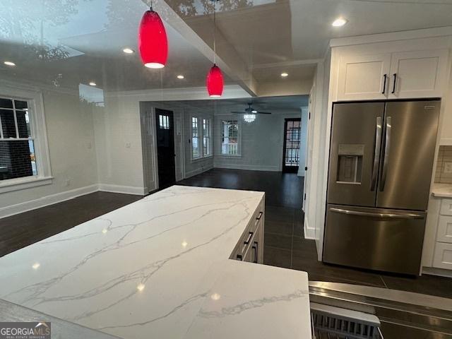 kitchen featuring white cabinetry, stainless steel fridge with ice dispenser, and light stone countertops