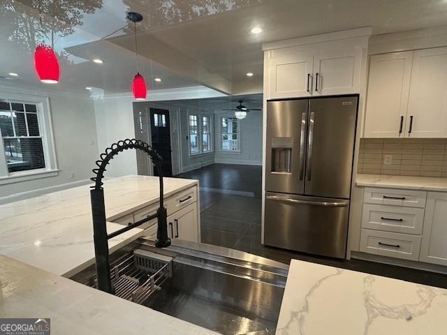 kitchen with white cabinetry, backsplash, hanging light fixtures, light stone countertops, and stainless steel fridge with ice dispenser