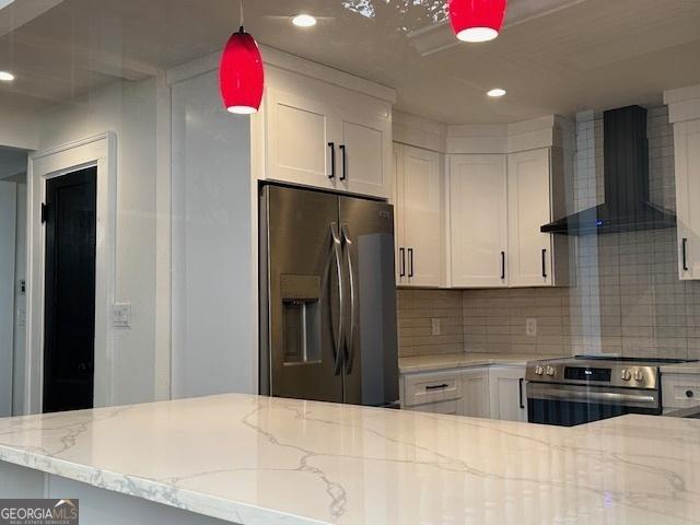 kitchen with tasteful backsplash, wall chimney range hood, stainless steel appliances, light stone countertops, and white cabinets